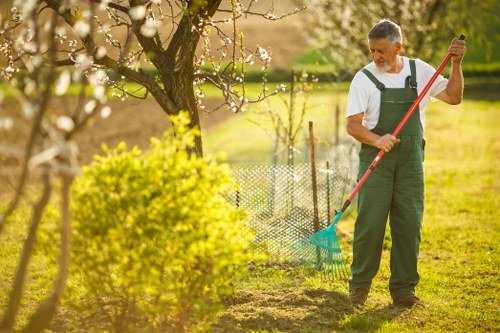 Trained gardener using pole hedge trimmer with protective equipment